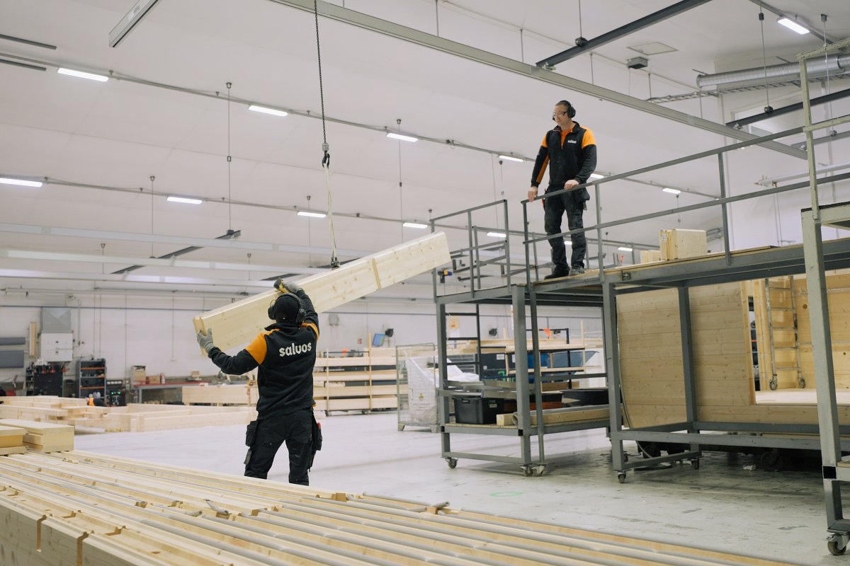 Salvos employees handling timber for a log frame in the factory production hall