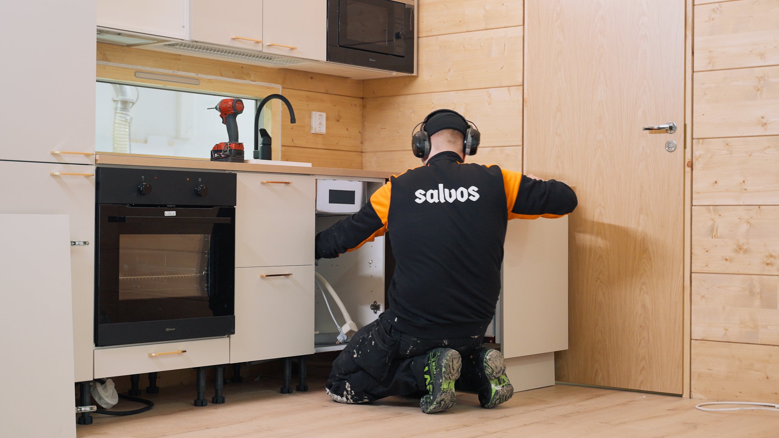 Salvos- The installer assembles kitchen cabinets and an oven inside the completed log building